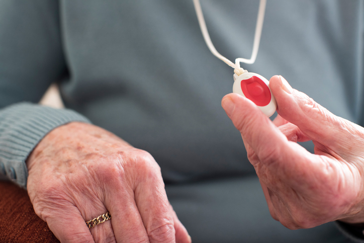 Close Up Of Unwell Senior Woman Holding Personal Alarm Button At Home